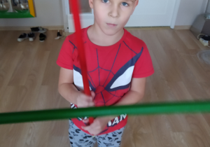 Chłopiec ćwiczy z kolorowymi patykami.